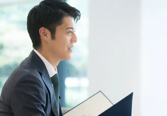 スーツ姿の男性が書類を手にして面談している様子