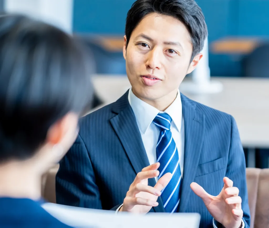 スーツを着たビジネスマンがオフィスでクライアントと話をしている様子