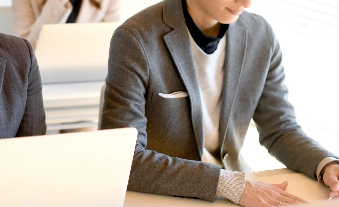 グレーのジャケットを着た男性がノートPCの前に座っている様子